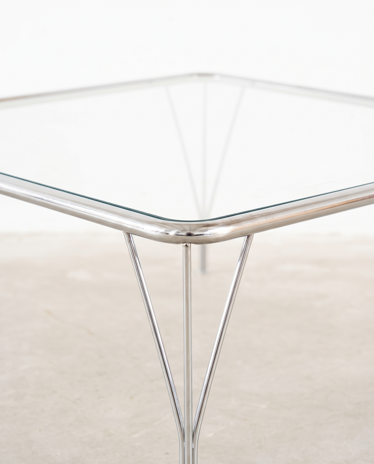 Detail of V-shaped chrome legs on glass coffee table